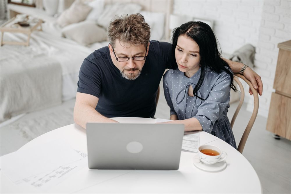 Couple working through plans together on a laptop at a kitchen table