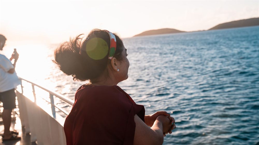 Woman watching the sea from a ship deck in warm evening light